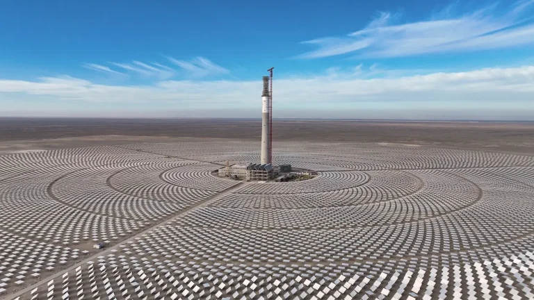 A panoramic view of a large solar farm in rural China, with rows of blue photovoltaic panels stretching across open land under clear skies, symbolising the country’s rapid expansion in renewable energy.